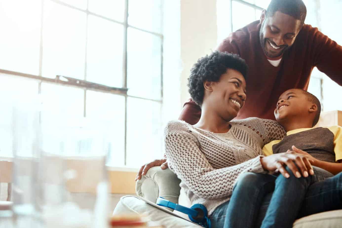 A happy African American family laughing in a light-filled living room; addiction support group.