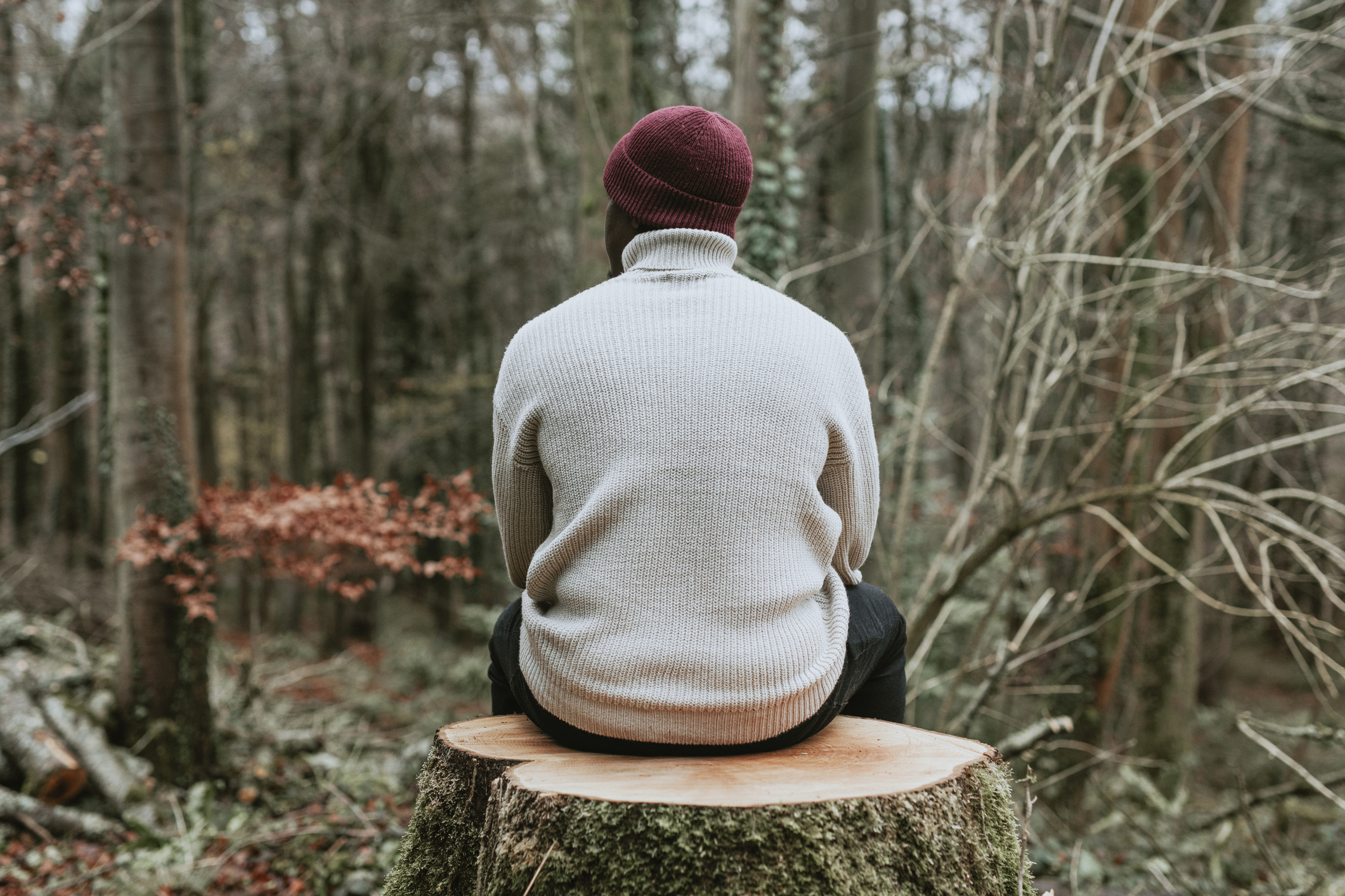 man sitting on tree stump in woods struggling with emotional abuse PTSD