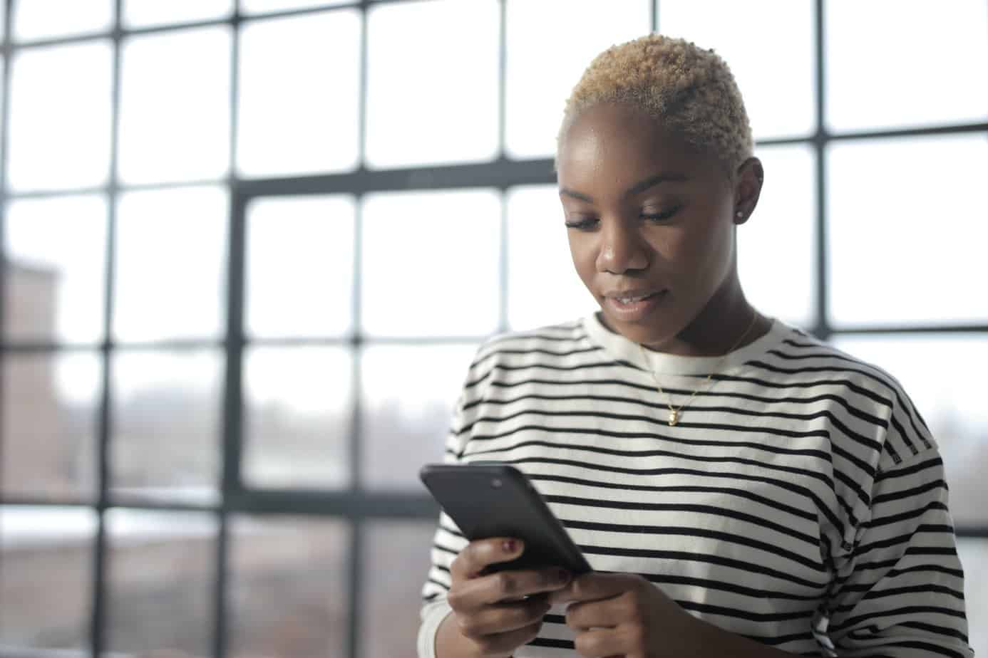 A Black woman looking at her mobile phone. Mountainside Recovery Helpline