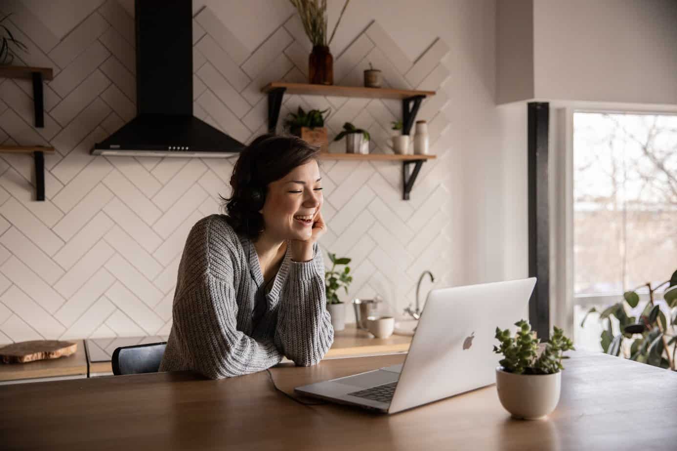 Happy woman using a laptop in her kitchen. Outpatient Addiction Treatment Service from Mountainside.